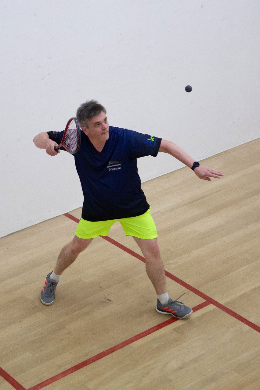 A KCC squash player prepares to strike the ball on court.